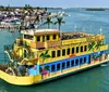 A brightly painted paddleboat with the name Calypso Breeze offering a tropical buffet is cruising near a waterfront with buildings and other boats in the background