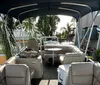 A group of people is enjoying a boat ride on a pontoon boat amidst a marina filled with various sailing boats on a sunny day