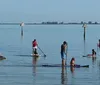 Two people are standing on paddleboards holding their paddles aloft on a calm water surface