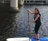 Two people are standing on paddleboards holding their paddles aloft on a calm water surface