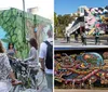 A group of cyclists are standing in front of a colorful intricate mural featuring psychedelic and vibrant imagery with the words Positive Creations and Peace Please