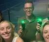 The image shows a group of five smiling people taking a group selfie at night with two of them holding devices that emit green lights