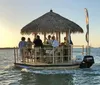 A group of people enjoys a gathering on a floating tiki bar boat at sunset