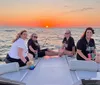 A group of individuals is enjoying a sunset on a boat with calm seas and a colorful sky in the background