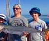 A man and a woman are smiling on a boat proudly displaying a large reddish fish they have caught