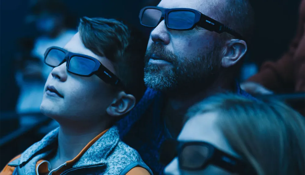 A man and a young boy wearing 3D glasses are watching something intently