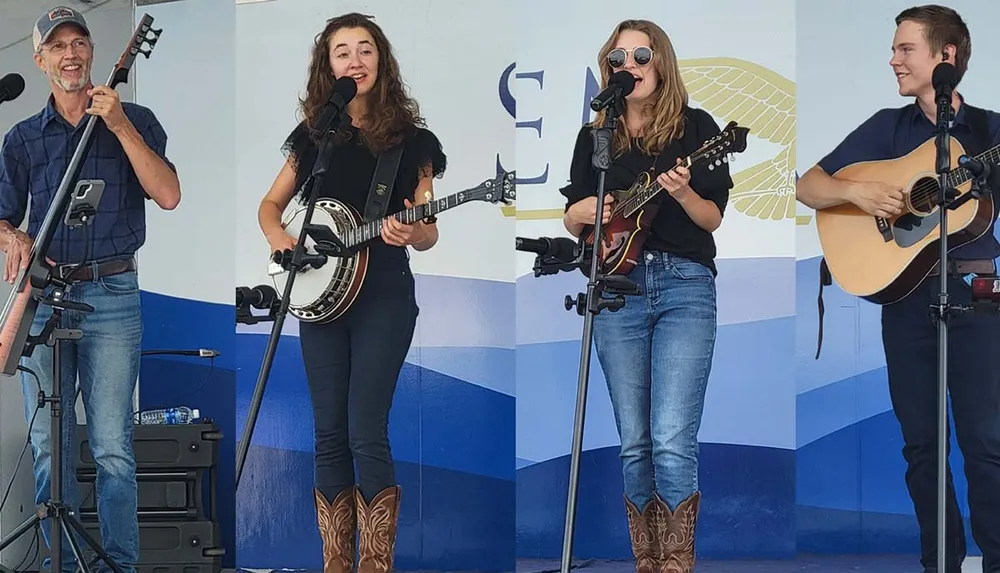 Four musicians perform on stage two with guitars one with a banjo and one with a bass in front of a backdrop with a stylized eagle design