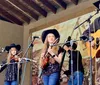 A group of musicians wearing cowboy hats is performing on stage with some playing stringed instruments and one singing into a microphone