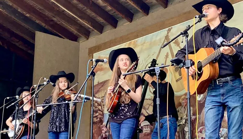 A group of musicians wearing cowboy hats is performing on stage with some playing stringed instruments and one singing into a microphone