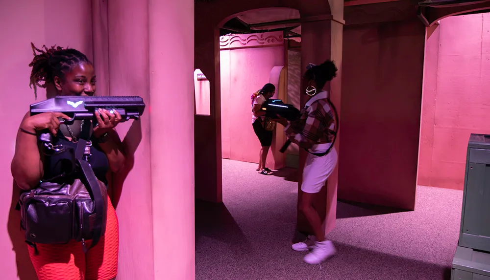 Two individuals are engaged in a laser tag game taking cover behind walls as they aim their laser guns