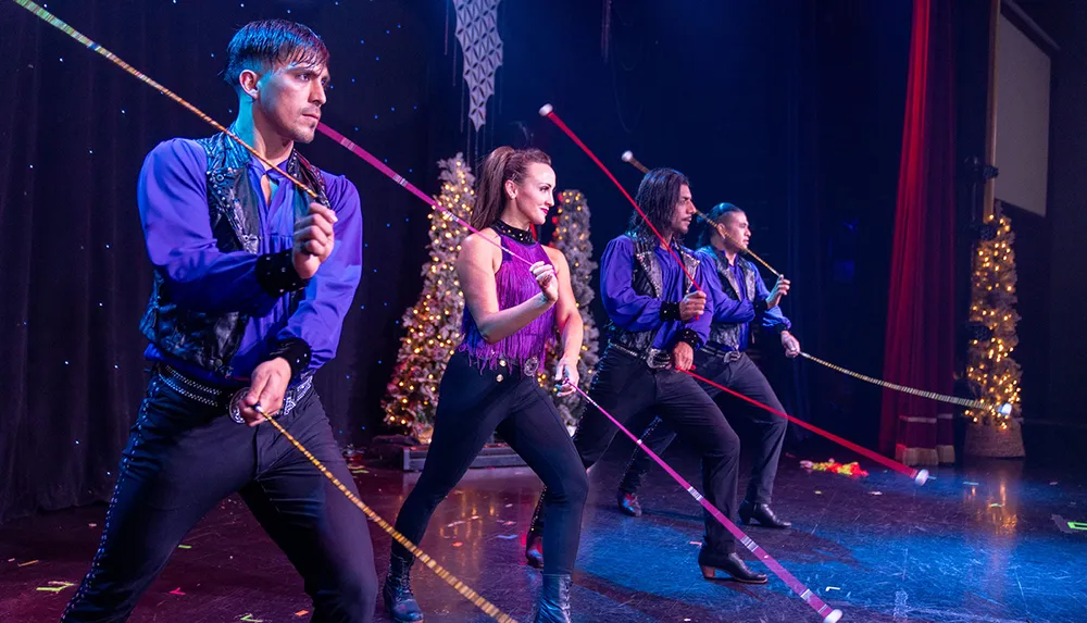 Four performers in matching costumes skillfully spin ropes on stage surrounded by festive decorations