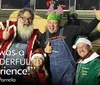 Four joyful people dressed in festive Christmas attire posing in front of a bus named BUS-TED