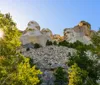 The image captures the sun shining through the trees beside the iconic Mount Rushmore National Memorial which features the carved faces of four former US presidents
