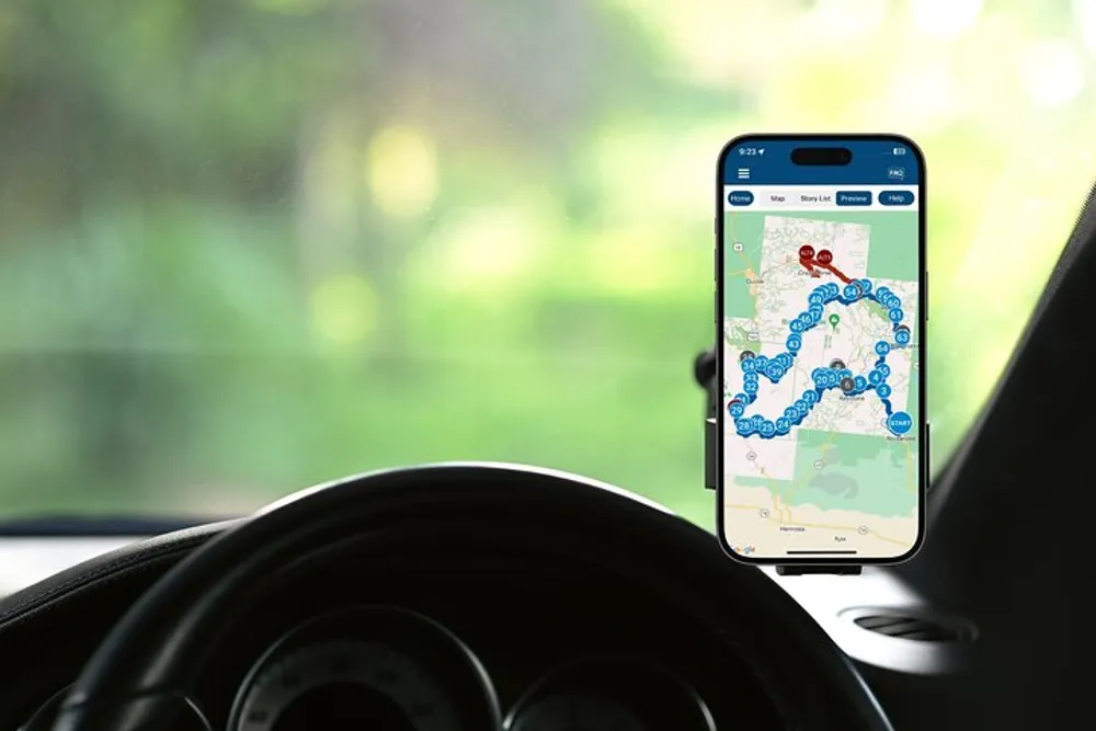 A smartphone with a navigation map on its screen is mounted on the dashboard of a car suggesting that the driver is using a GPS application for directions