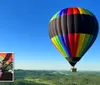 A colorful hot air balloon is soaring over a landscape with a small inset of a smiling couple taking a selfie inside it