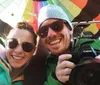 A colorful hot air balloon is soaring over a landscape with a small inset of a smiling couple taking a selfie inside it