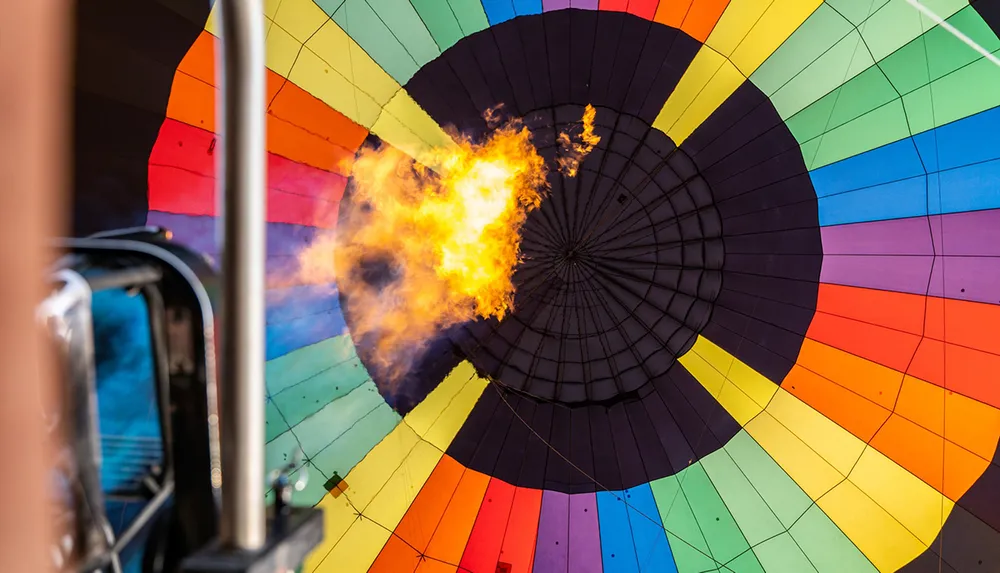 The image shows the inside of a colorful hot air balloon being inflated with a burst of flame