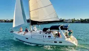 A group of people is enjoying a sunny day out on the water aboard a sailboat named “Star of Orion”.