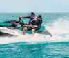 Two people are riding on a jet ski across clear blue waters creating a spray as they move