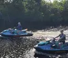 A group of people wearing life vests are posing with their personal watercraft on a sunny day near the shore