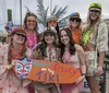 A group of people in colorful attire holding a sign that says Gettin Freaky on the Tiki are posing happily for a photo