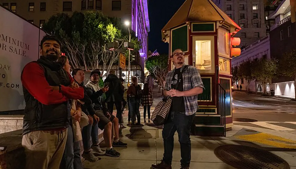 A group of people wait at night next to a vintage-style cable car stop illuminated by street lights and neon accents