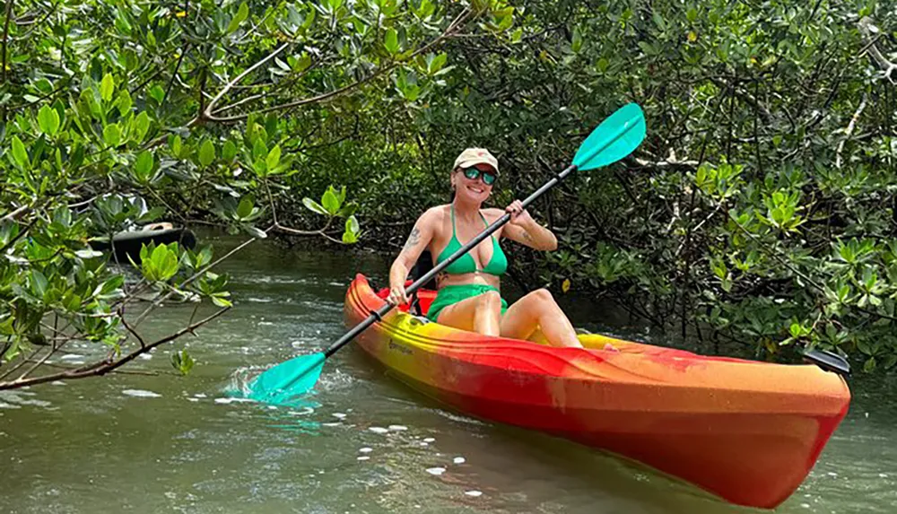 A person is happily kayaking through a mangrove forest