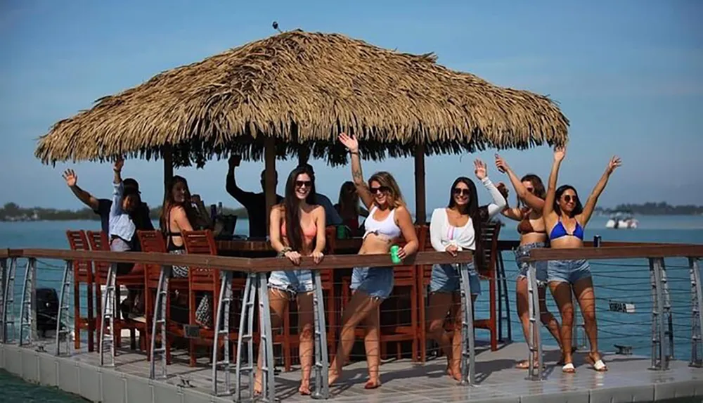 A group of people are enjoying themselves at a tiki bar set atop a floating platform on the water