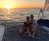 A man and a woman are smiling for the camera with a beautiful sunset over the ocean in the background