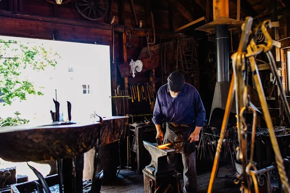 A person is forging a hot metal on an anvil inside a traditional blacksmith shop