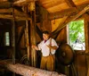 A person in historical attire is giving a demonstration or presentation in a rustic wooden interior possibly a historic or educational setting