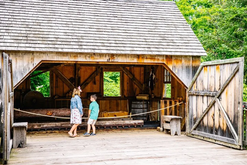 Two individuals are having a conversation inside an open rustic wooden structure with historical artifacts