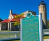 The image features the Old Mackinac Point Lighthouse and its informative sign under a clear blue sky