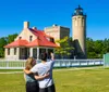 The image features the Old Mackinac Point Lighthouse and its informative sign under a clear blue sky