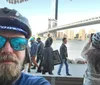 Three people wearing bicycle helmets are posing for a photo with a backdrop of the Brooklyn Bridge and New York City skyline