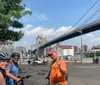 Three people wearing bicycle helmets are posing for a photo with a backdrop of the Brooklyn Bridge and New York City skyline