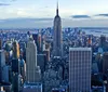 The image showcases a sweeping aerial view of New York Citys skyline with the Empire State Building prominently centered and the Hudson River in the background