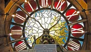 The image depicts a colorful stained glass window with a unique abstract design, enhanced by the natural light shining through it.