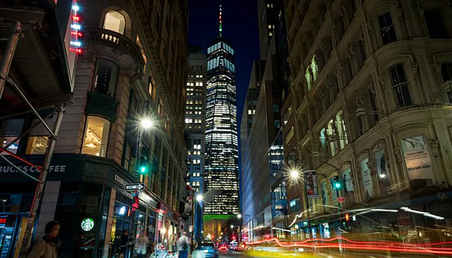 The image shows a bustling urban night scene with illuminated buildings and the light trails of moving vehicles on a busy street.