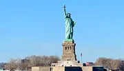 The image features the Statue of Liberty against a clear blue sky, symbolizing freedom and democracy.