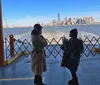 Two people are conversing on a ferry with the New York City skyline in the background