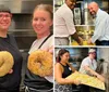 Three smiling people are holding up large seeded bagels toward the camera in a kitchen setting