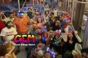 A group of people appear to be enjoying a social event at night, wearing glowing headbands and accessories, with a logo and text 