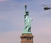 A ferry filled with passengers sails near the Statue of Liberty on a cloudy day