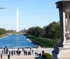 The image shows a bustling scene at the National Mall in Washington DC with a view of the Washington Monument the Reflecting Pool visitors and a helicopter flying overhead