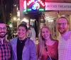 Four smiling individuals are posing for a photo in front of a venue advertising live music with the neon sign Casbah located above The Players Theatre