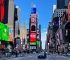 The image captures the vibrant atmosphere of Times Square in New York City bustling with pedestrians and adorned with iconic illuminated billboards under a clear blue sky