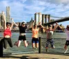 A group of five people are posing for a photo on the Brooklyn Bridge with the New York City skyline in the background