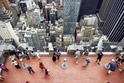 Visitors are enjoying an aerial view of a dense urban skyline from a high observation deck.