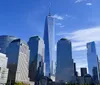 The image shows the Lower Manhattan skyline with One World Trade Center standing tall against a clear blue sky